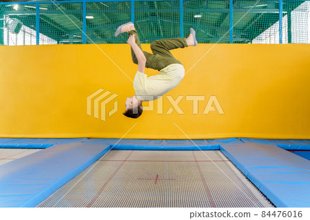 Teenage boy jumping on trampoline park in sport center  84476016