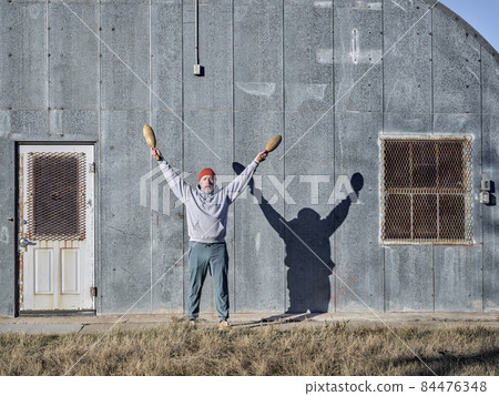 senior athletic male is exercising with wooden Indian clubs senior athletic male is exercising with wooden Indian clubs 84476348