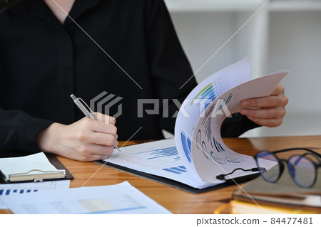 Cropped shot female accountant holding pen and signing on document. Cropped shot female accountant holding pen and signing on document. 84477481