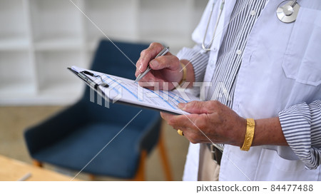 Cropped shot senior doctor in white uniform working in medical office. 84477488