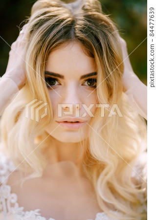 Portrait of the bride in a white dress and veil. Close-up Portrait of the bride in a white dress and veil. Close-up 84477639
