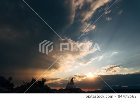 The bride stands on the rocks in the picturesque mountains in Montenegro at the sunset The bride stands on the rocks in the picturesque mountains in Montenegro at the sunset 84478562
