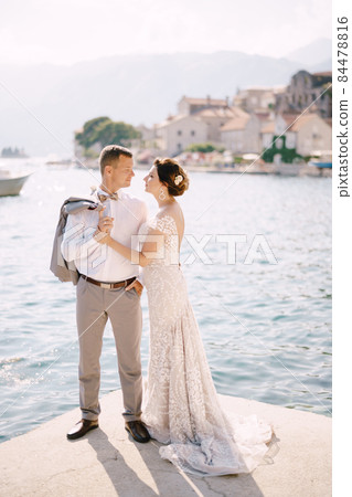 Groom and bride stand on the pier looking each other 84478816