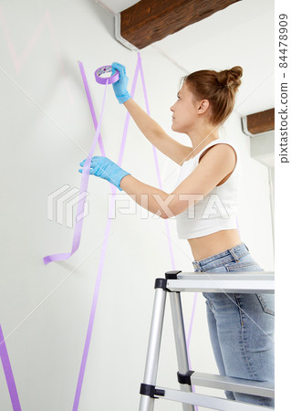 Young woman with paint brush painting wall in a new house. Home decoration concept Young woman with paint brush painting wall in a new house. Home decoration concept 84478909