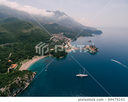 Sailboat sails along the bay to the royal beach. Villa Milocer, Montenegro Sailboat sails along the bay to the royal beach. Villa Milocer, Montenegro 84479141