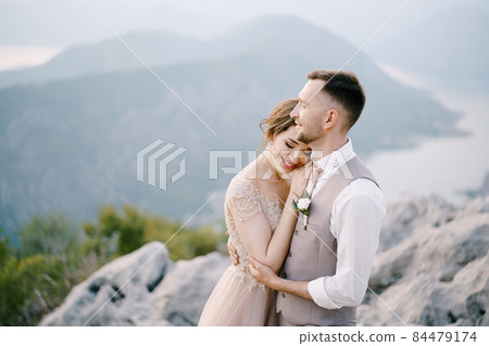Smiling groom embraces bride on the mountain. Portrait Smiling groom embraces bride on the mountain. Portrait 84479174