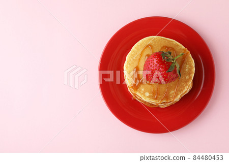 Plate with pancakes with strawberry and caramel on pink background 84480453