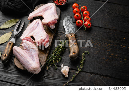 Raw duck wings, on black wooden table background, with copy space for text 84482005