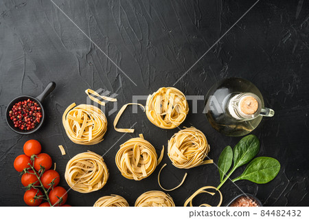 Cooking tagliatelle pasta and ingredients, on black stone background, top view flat lay, with copy space for text Cooking tagliatelle pasta and ingredients, on black stone background, top view flat lay, with copy space for text 84482432