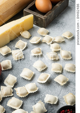 Italian Ravioli ingredients with fresh ricotta leaves and tomatoes, on gray background 84482486