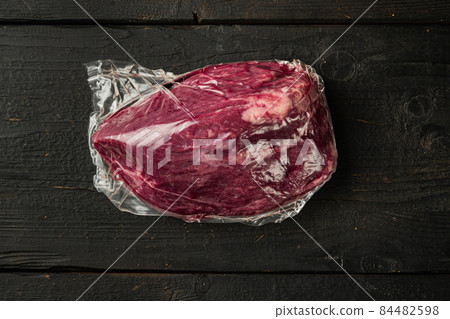 Vacuum packed organic raw beef, on black wooden table background, top view flat lay 84482598