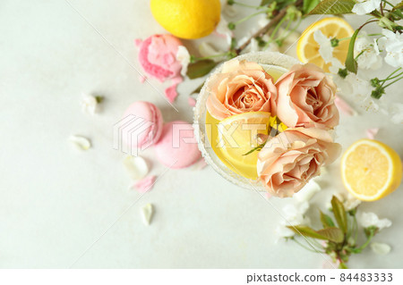 Glass of cocktail, ingredients and flowers on white textured table Glass of cocktail, ingredients and flowers on white textured table 84483333