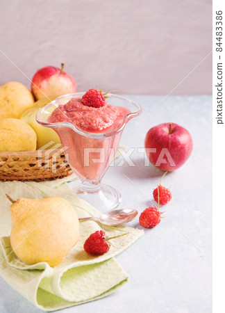 Fruit smoothie- apples, pears and raspberries in a glass glass on a light background. Fruit in a wicker plate on the table. Fruit smoothie- apples, pears and raspberries in a glass glass on a light background. Fruit in a wicker plate on the table. 84483386