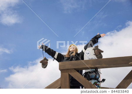 Snowboarder woman looking up at the sky at a ski lodge 84483840