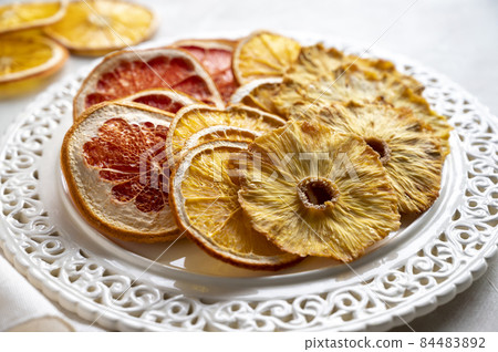 Homemade organic dried fruit slices of orange, grapefruit, pineapple in a plate. Healthy snack or dessert. Homemade organic dried fruit slices of orange, grapefruit, pineapple in a plate. Healthy snack or dessert. 84483892