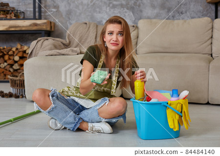 Woman housewife feel tired sitting on floor at living room after cleaning at home. 84484140