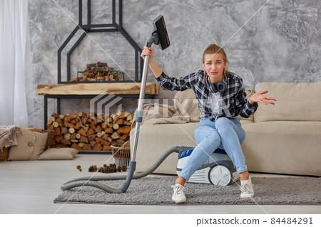 Young woman with cleaning equipment ready to clean house, sitting on couch. Fatigue 84484291