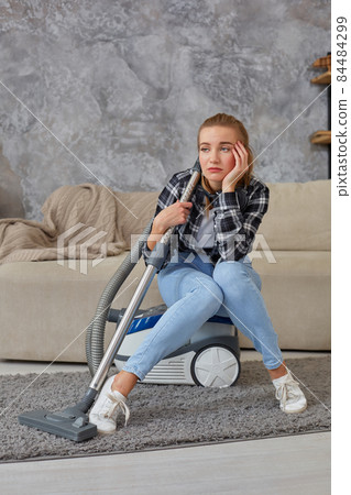 Young woman with cleaning equipment ready to clean house, sitting on couch. Fatigue Young woman with cleaning equipment ready to clean house, sitting on couch. Fatigue 84484299