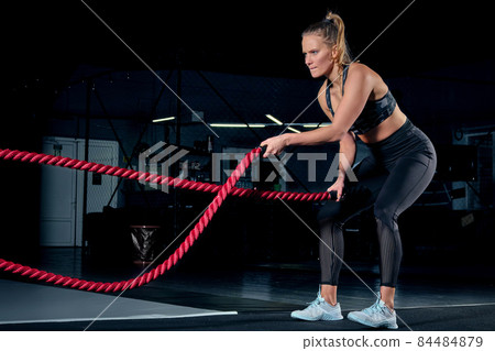 Athlete working out with battle ropes at cross gym. 84484879