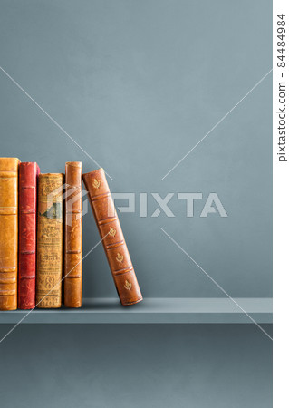 Row of old books on grey shelf. Vertical background 84484984