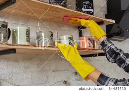 Woman in gloves cleaning furniture with rag at home kitchen. Woman in gloves cleaning furniture with rag at home kitchen. 84485530