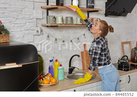 Woman in gloves cleaning furniture with rag at home kitchen. Woman in gloves cleaning furniture with rag at home kitchen. 84485552