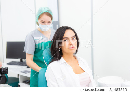 The dentist's assistant puts a protection on the patient, a napkin on the chest. Preparing for dental treatment The dentist's assistant puts a protection on the patient, a napkin on the chest. Preparing for dental treatment 84485813