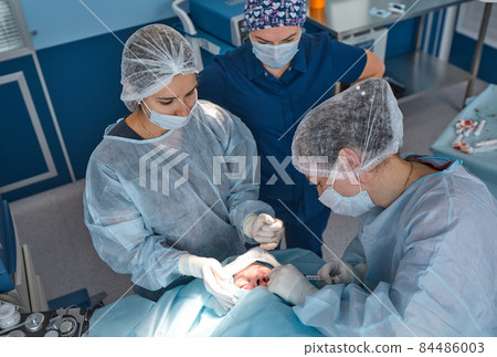 Close up of the face of a patient who is undergoing blepharoplasty. The surgeon cuts the eyelid and performs manipulations using medical instruments 84486003