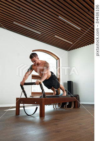 Pilates reformer workout exercises man at gym indoor. Pilates reformer workout exercises man at gym indoor. 84486106