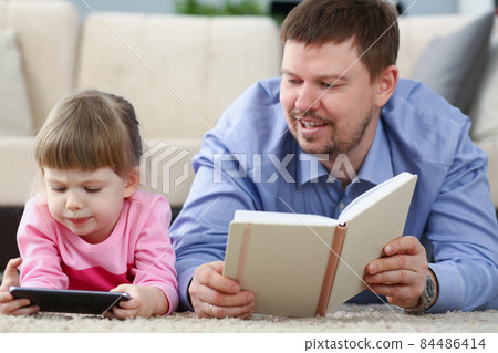 Father reading book to daughter while child stare at smartphone 84486414