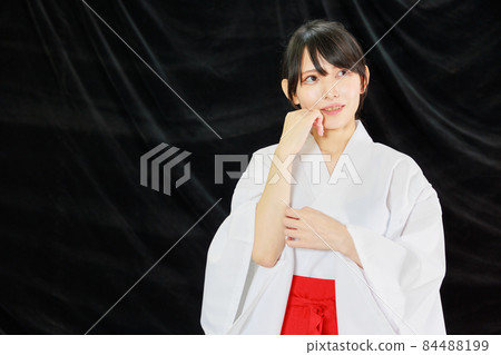 Japanese woman wearing shrine maiden clothes in black background 84488199