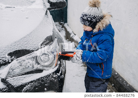 Cute little boy cleaning snow off the car at winter backyard. Little kid Toddler boy helping father to clear car of snow and using brush tool for cleaning car Cute little boy cleaning snow off the car at winter backyard. Little kid Toddler boy helping father to clear car of snow and using brush tool for cleaning car 84488276