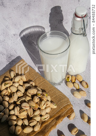 Glass of healthy pistachio milk stands on concrete background. Diet milk, vegetarian food. Gluten free. Close-up. Pistachio lactose free milk for dietary nutrition. Alternative food and vegetarianism. 84488732