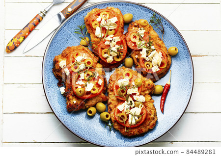 Meat schnitzel with cheese, olives and tomato 84489281