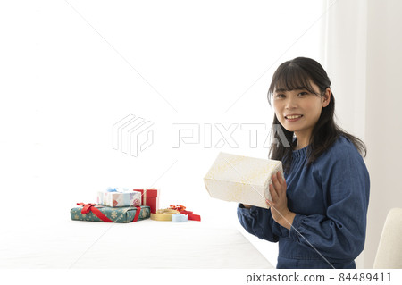 A woman wrapping a gift in wrapping paper at the living room table 84489411