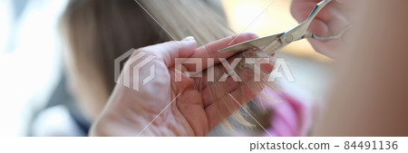 Master hairdresser cuts split ends of hair with scissors closeup 84491136
