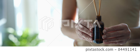 Bottle with incense sticks in female hands closeup Bottle with incense sticks in female hands closeup 84491141