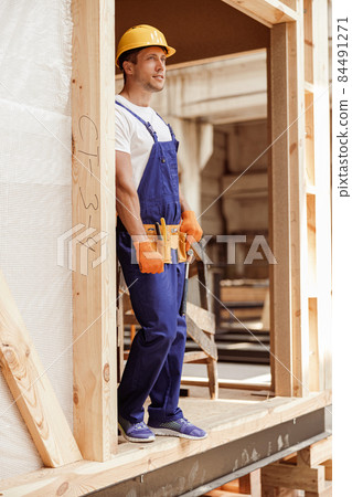 Male builder in work overalls standing in construction cabin 84491271