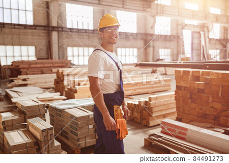 Cheerful male worker standing by construction materials Cheerful male worker standing by construction materials 84491273