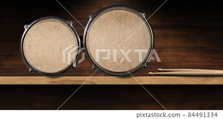 Bongo Drums and Drumsticks on Wooden Shelf - Percussion instrument 84491334