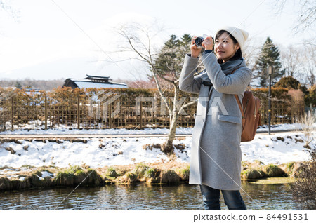 A woman enjoying winter sightseeing while holding a camera A woman enjoying winter sightseeing while holding a camera 84491531