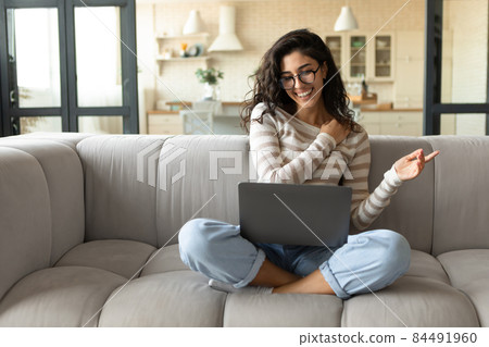 Remote business. Young freelancer woman working on laptop, sitting on couch at home, communicating with colleagues 84491960