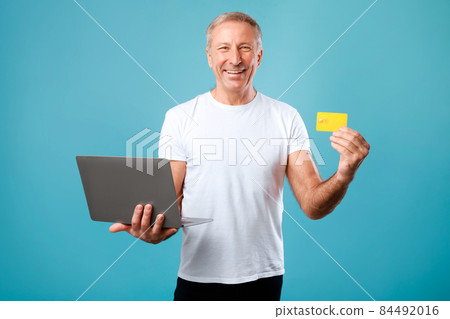 Excited mature man holding credit card and laptop Excited mature man holding credit card and laptop 84492016