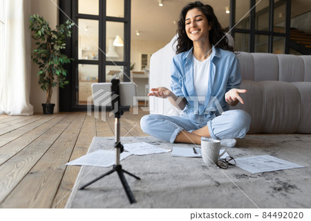 Millennial female teacher conducting online lesson on cellphone camera, blogger streaming on social media at home Millennial female teacher conducting online lesson on cellphone camera, blogger streaming on social media at home 84492020