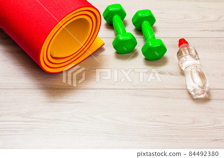 Yoga mat and different tools for fitness on floor in room. 84492380