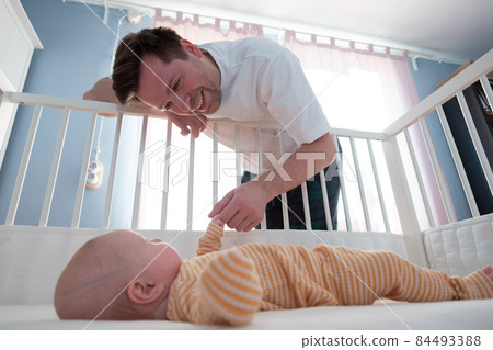 Young man playing with his little baby in bed 84493388