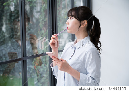 一個女人用一隻手用智能手機刷牙 一個女人用一隻手用智能手機刷牙 84494135