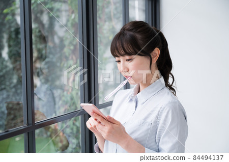 一個女人用一隻手用智能手機刷牙 一個女人用一隻手用智能手機刷牙 84494137