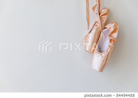 New pastel beige ballet shoes with satin ribbon isolated on white background. Ballerina classical pointe shoes for dance training. Ballet school concept. Copy space 84494488