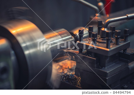 A heavy industrial worker in a factory works with metal on angle grinders while hot sparks are produced as a result. A heavy industrial worker in a factory works with metal on angle grinders while hot sparks are produced as a result. 84494794